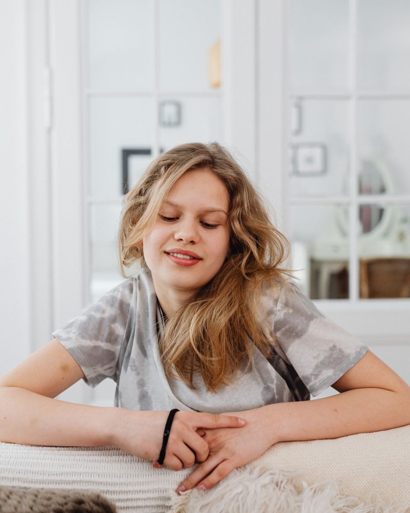 Adolescente rubia sentada con calma y expresión serena en una habitación luminosa con luz natural cálida, terapia de la depresión en adolescentes en Komit Psicología