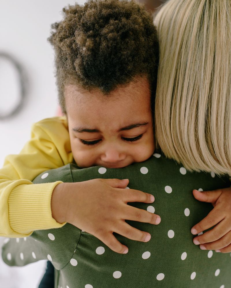 Niño pequeño llorando abrazado con ternura por su madre que lo calma, acompañamiento para rabietas infantiles en Komit Psicología
